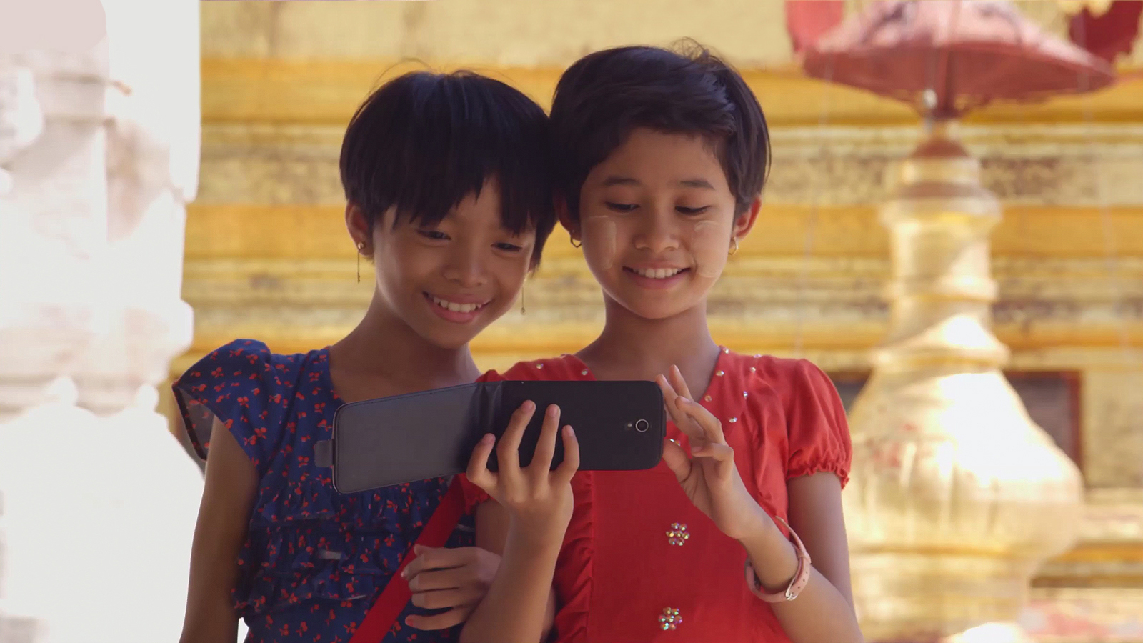 Two young girls looking at a phone together. 