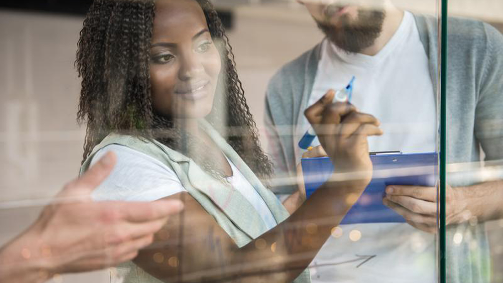 Woman writing on a clear board.