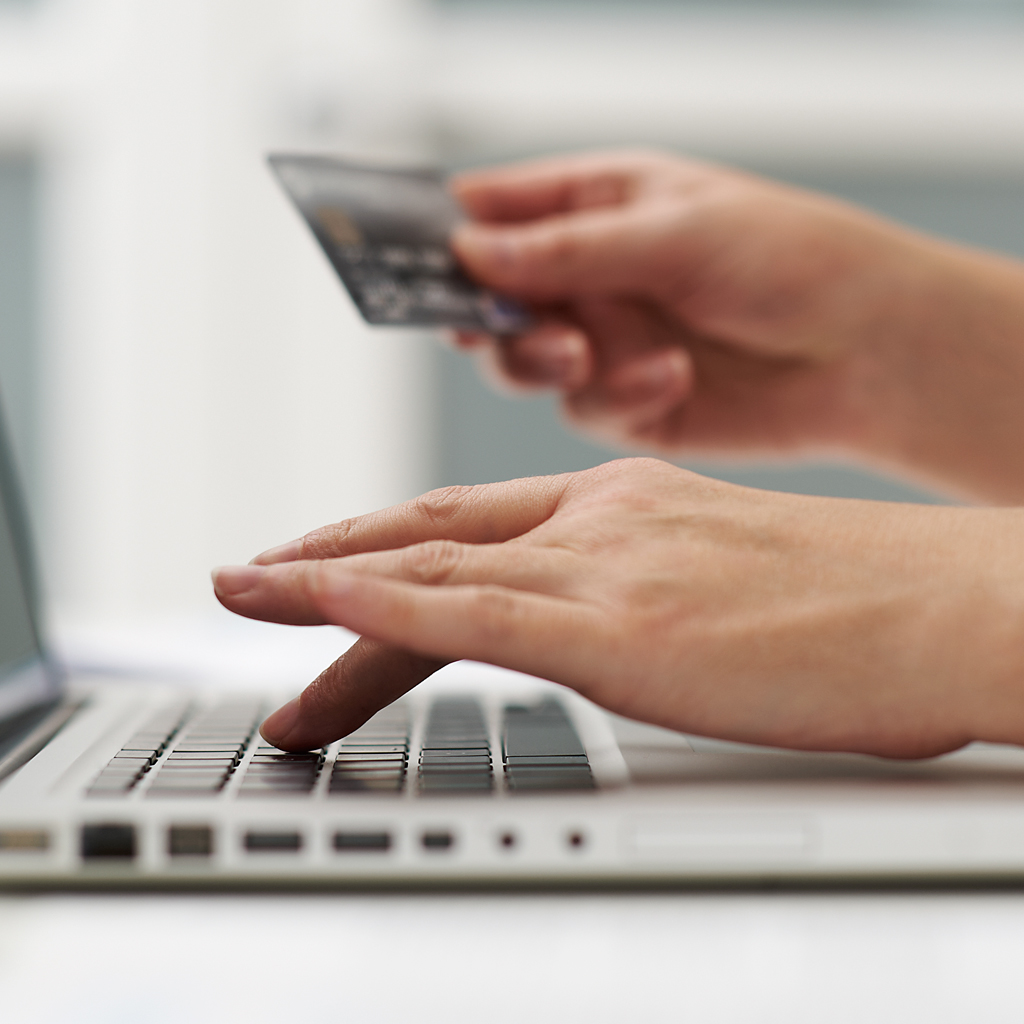 Close up of a woman on her laptop holding her Visa card