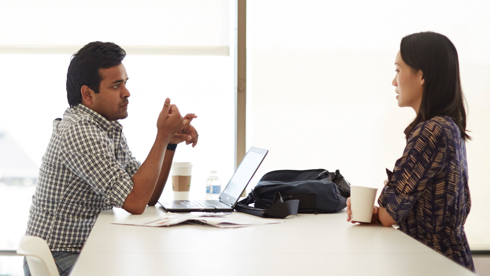 A man and a woman sitting at a table and having a conversation.