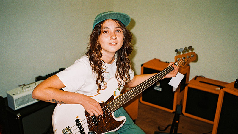 Young woman playing electric bass guitar in a rehearsal studio.